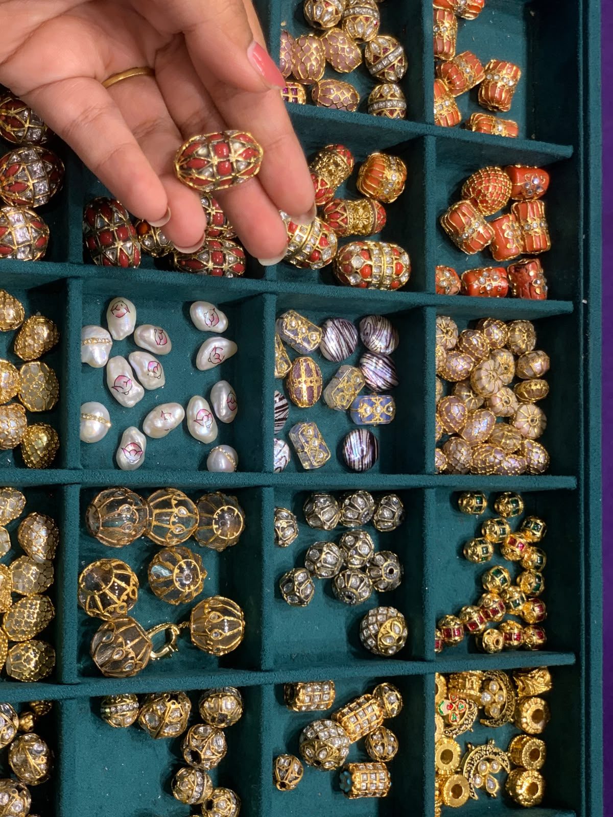 Artisan hand sorting kundan stones in a velvet tray